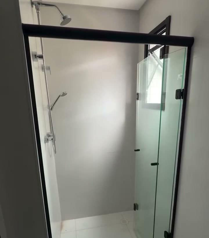 Box de vidro com perfis pretos num banheiro branco