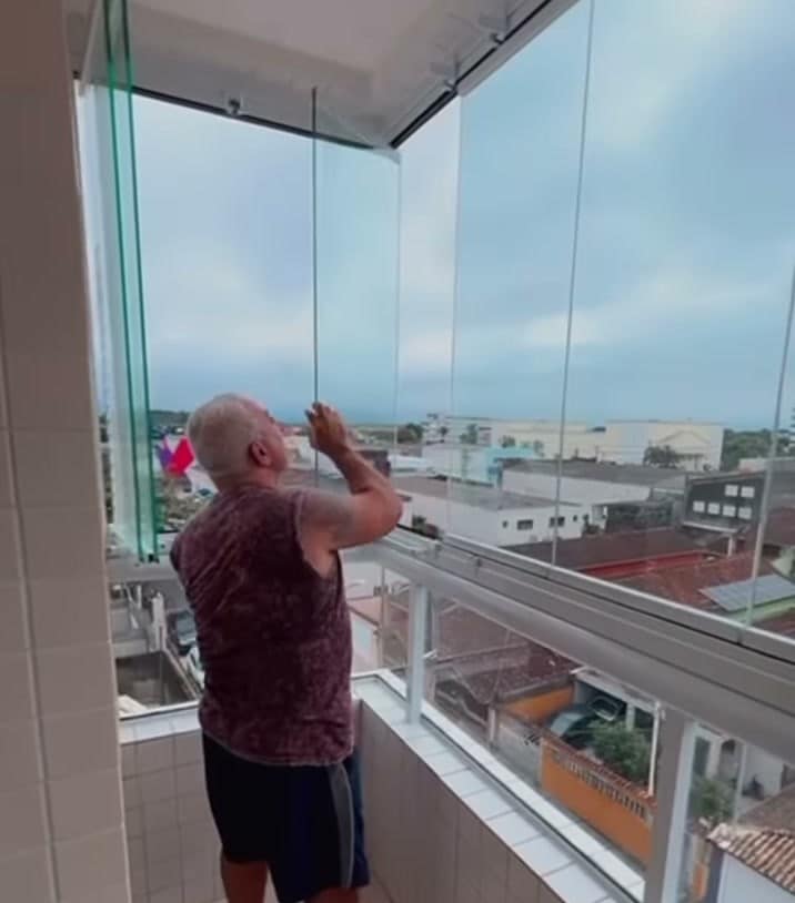 Painel de vidro sendo recolocado no trilho durante a manutenção