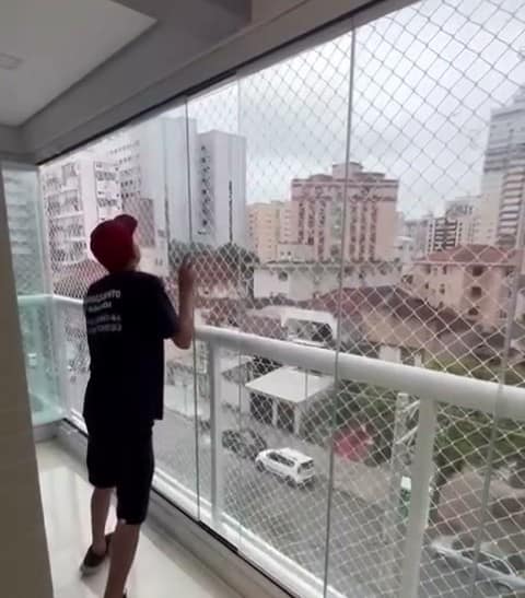 Instalador ajustando um painel de vidro numa sacada alta