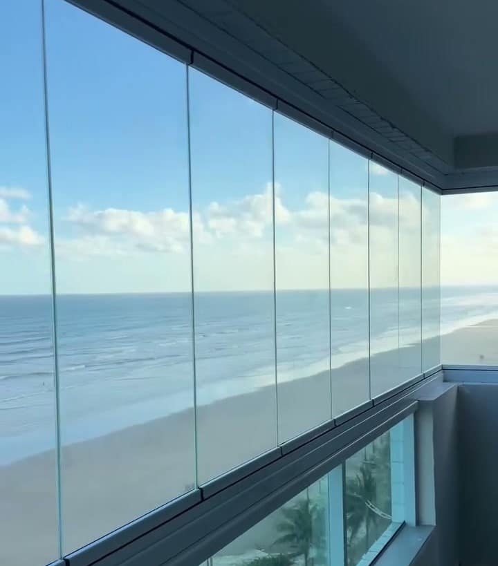Sacada de frente para o mar com os painéis de vidro recolhidos para o lado