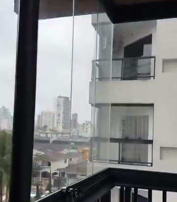 Sacada envidraçada no fim da tarde, com o sol baixo sobre a cidade