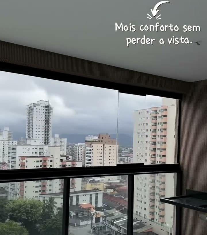Sacada com envidraçamento de perfis pretos, vista para os prédios