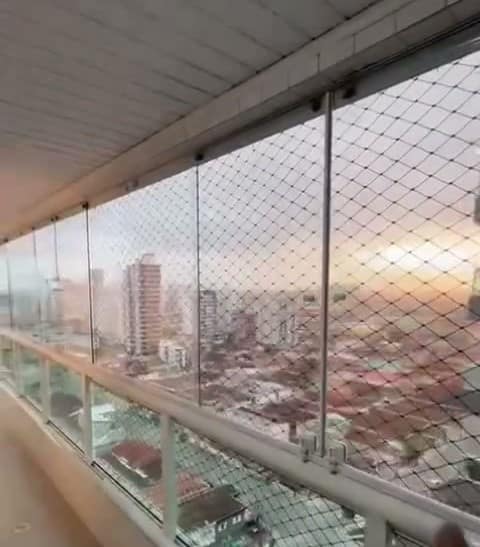 Sacada envidraçada com tela de proteção e vista para a cidade