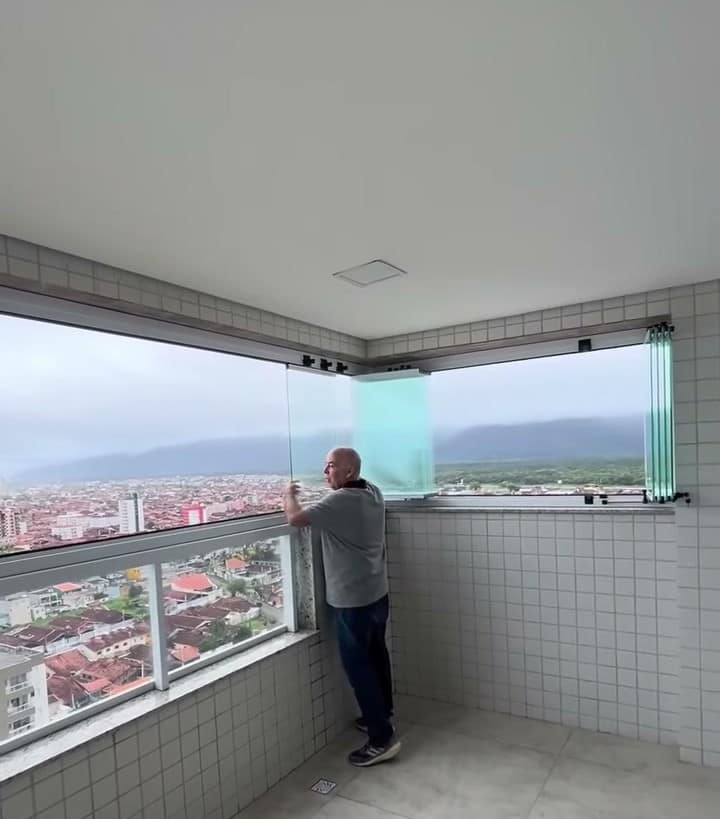 Sacada envidraçada com vista para a cidade e a praia, vidros fechados